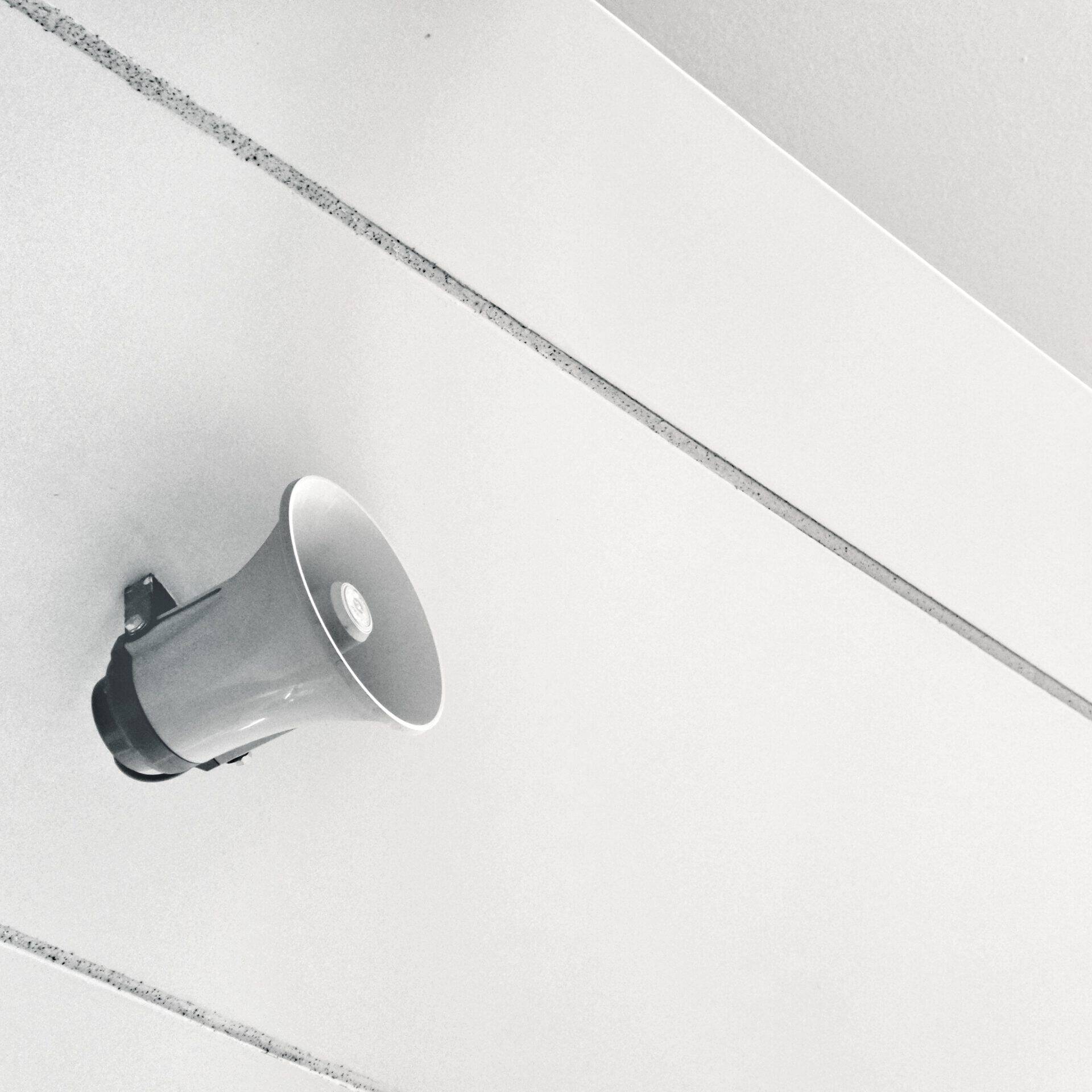 ein an einer weißen Wand montierter weißer Lautsprecher leitet den Expert:innen Beitrag ein, warum Kommunikation für erfolgreiche Veränderungsprozesse so wichtig ist.