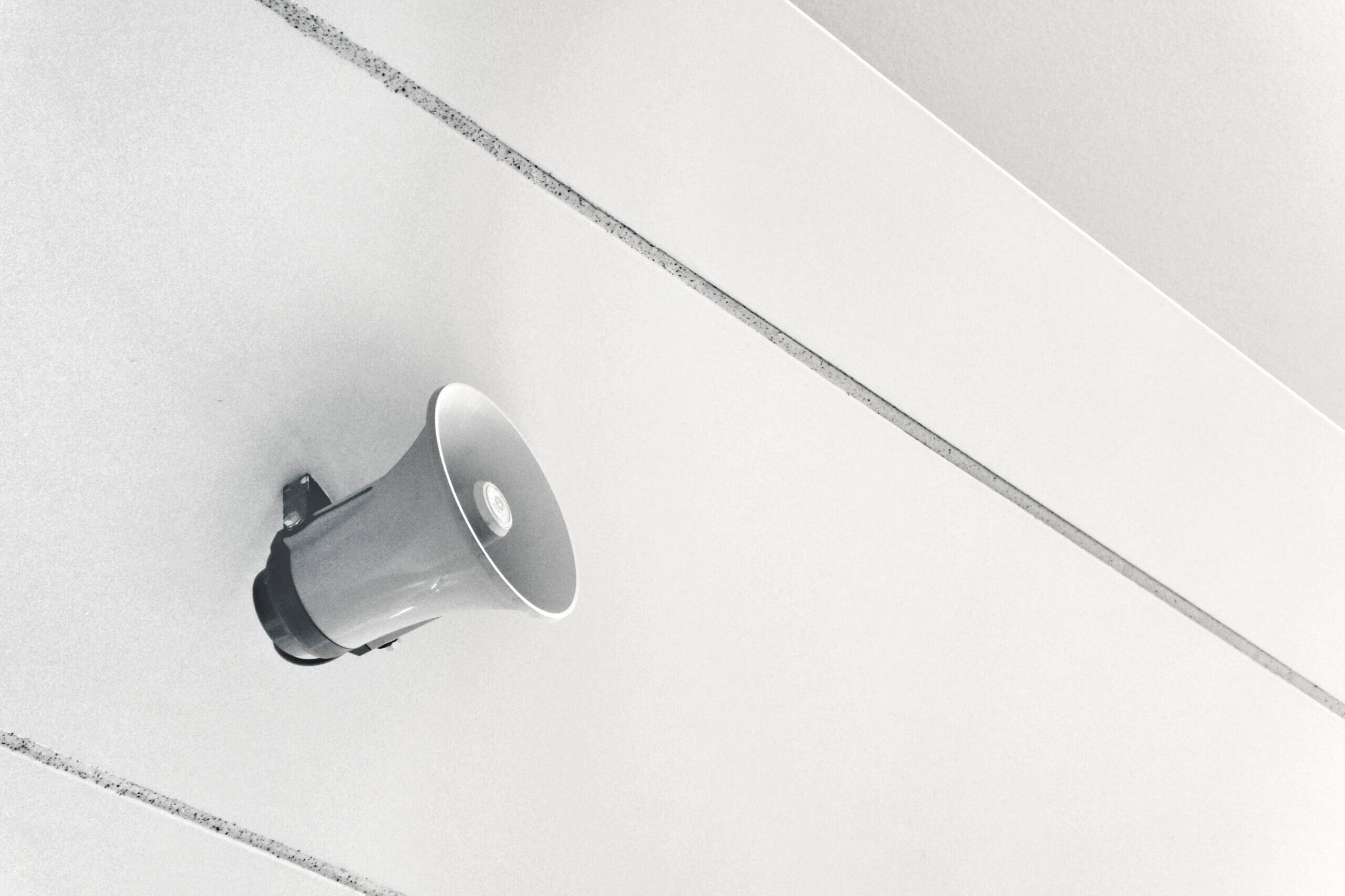 ein an einer weißen Wand montierter weißer Lautsprecher leitet den Expert:innen Beitrag ein, warum Kommunikation für erfolgreiche Veränderungsprozesse so wichtig ist.